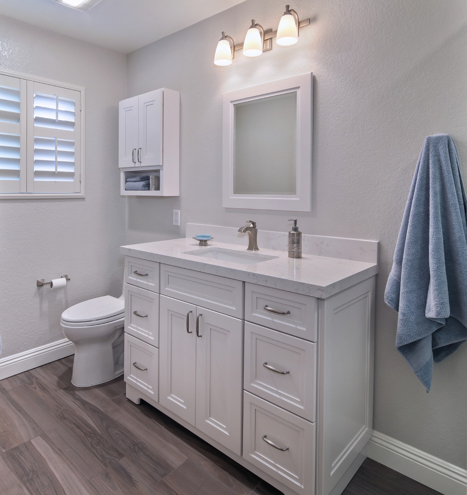 Inspiration for a mid-sized transitional 3/4 bathroom in Orange County with shaker cabinets, white cabinets, an alcove shower, a one-piece toilet, blue tile, porcelain tile, grey walls, porcelain floors, an undermount sink and engineered quartz benchtops.