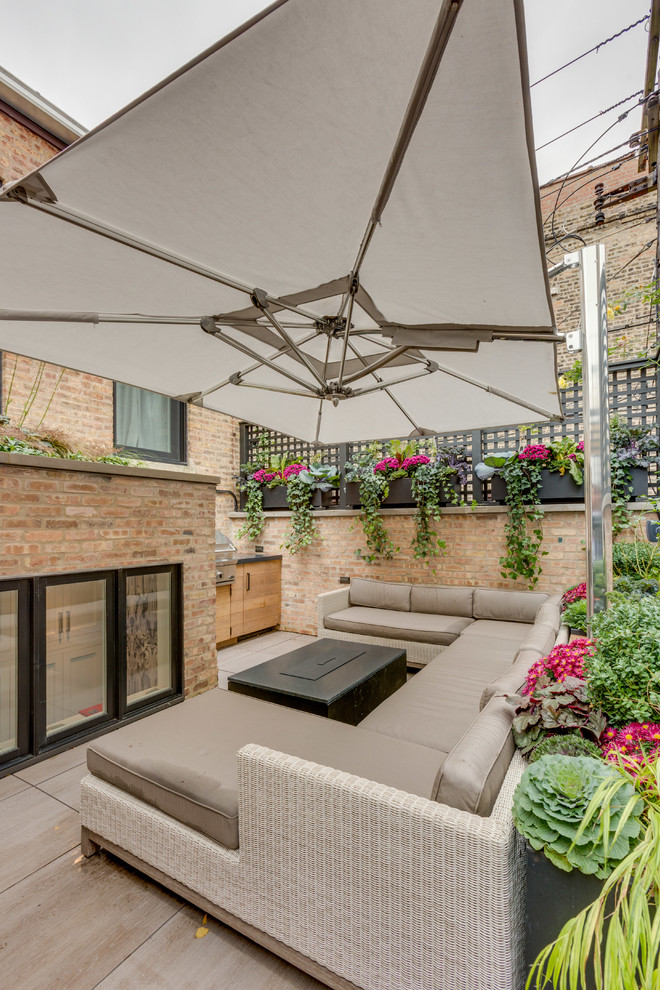 Photo of a modern backyard patio in Chicago with an outdoor kitchen and an awning.