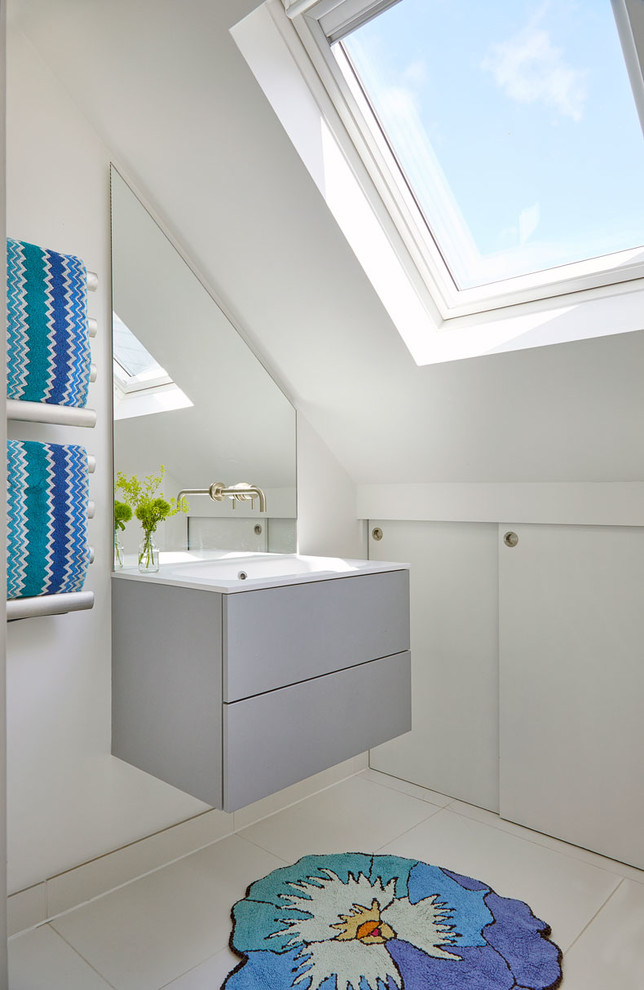 This is an example of a contemporary powder room in London with flat-panel cabinets, grey cabinets, white walls, a console sink and white floor.