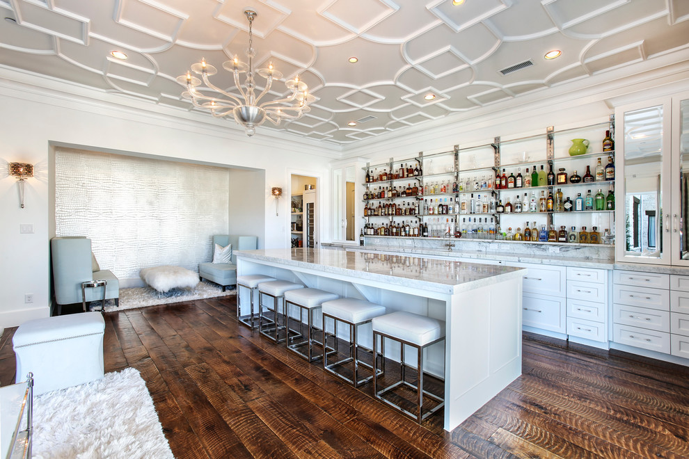 Design ideas for an expansive transitional single-wall seated home bar in Dallas with an undermount sink, recessed-panel cabinets, white cabinets, marble benchtops, white splashback, stone tile splashback, medium hardwood floors, brown floor and white benchtop.