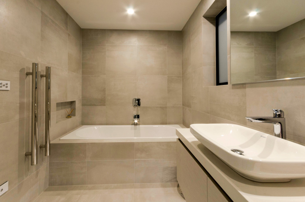 This is an example of a large contemporary kids bathroom in Auckland with recessed-panel cabinets, grey cabinets, a freestanding tub, a corner shower, a wall-mount toilet, gray tile, stone tile, grey walls, cement tiles, a vessel sink, engineered quartz benchtops, grey floor, a hinged shower door, white benchtops, a single vanity and a floating vanity.