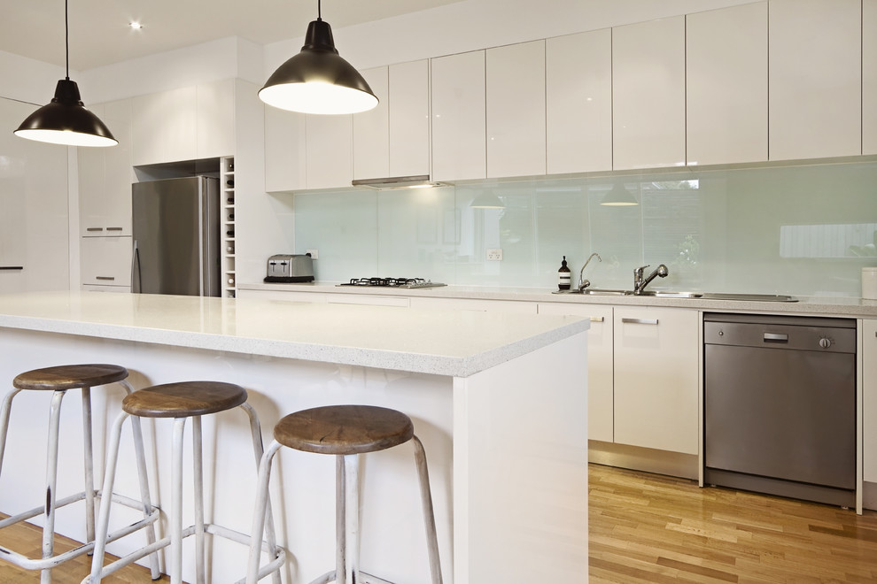 This is an example of a modern eat-in kitchen in Newcastle - Maitland with green splashback and glass sheet splashback.