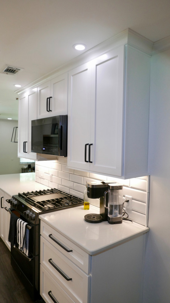 Mid-sized transitional galley porcelain tile and gray floor eat-in kitchen photo with an undermount sink, shaker cabinets, white cabinets, quartz countertops, white backsplash, subway tile backsplash, black appliances, no island and white countertops