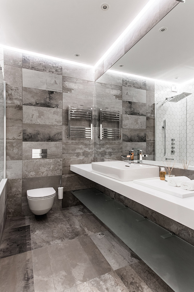 Photo of a mid-sized contemporary master bathroom in Other with an alcove tub, a wall-mount toilet, gray tile, porcelain tile, porcelain floors, grey floor, open cabinets and a vessel sink.