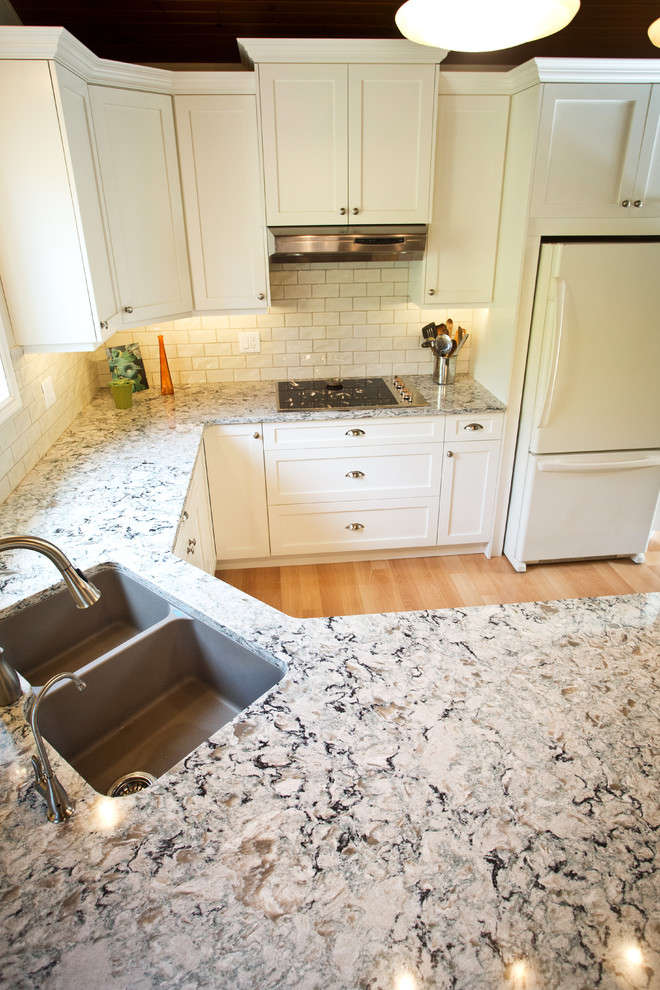 Kitchen - mid-sized transitional u-shaped light wood floor kitchen idea in Toronto with an undermount sink, shaker cabinets, white cabinets, granite countertops, white backsplash, subway tile backsplash, white appliances and a peninsula