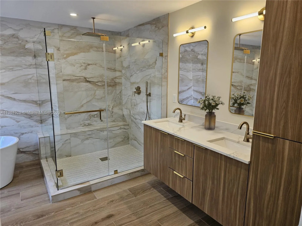 This is an example of an expansive contemporary master bathroom in Miami with flat-panel cabinets, medium wood cabinets, a freestanding tub, a corner shower, white tile, porcelain tile, white walls, porcelain floors, a drop-in sink, engineered quartz benchtops, grey floor, a hinged shower door, yellow benchtops, a double vanity and a built-in vanity.
