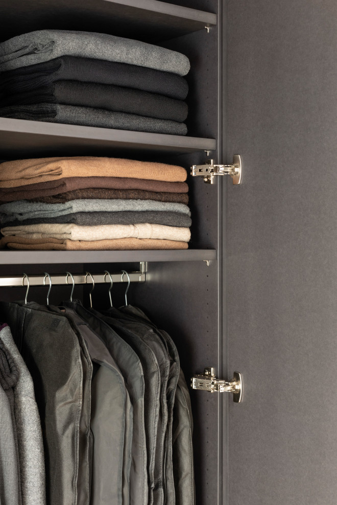 This is an example of a mid-sized modern gender-neutral walk-in wardrobe in Stuttgart with flat-panel cabinets, black cabinets, light hardwood floors, brown floor and exposed beam.