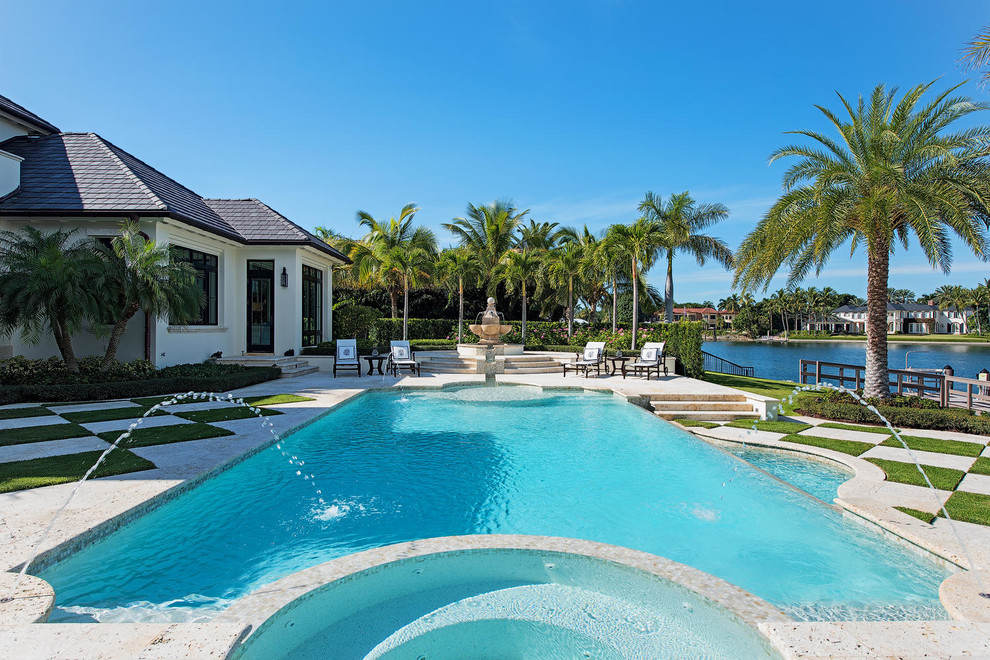 Design ideas for an expansive beach style backyard custom-shaped infinity pool in Miami with a water feature and natural stone pavers.