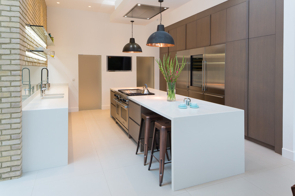 Inspiration for a large contemporary galley open plan kitchen in London with an integrated sink, flat-panel cabinets, dark wood cabinets, quartzite benchtops, green splashback, glass sheet splashback, panelled appliances, ceramic floors, with island, white floor and white benchtop.