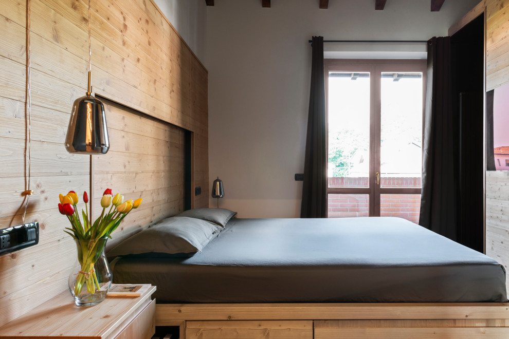 Modelo de dormitorio principal rural pequeño con paredes grises, suelo laminado, suelo marrón, madera y madera