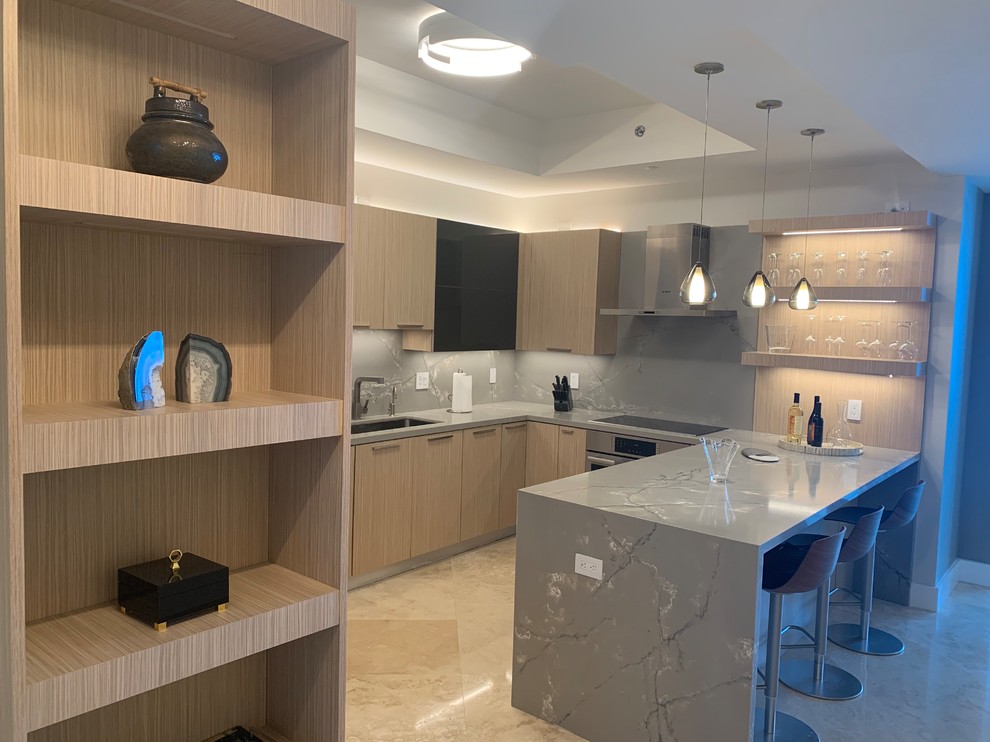 Design ideas for a mid-sized contemporary u-shaped eat-in kitchen in Miami with an undermount sink, flat-panel cabinets, light wood cabinets, quartzite benchtops, grey splashback, stone slab splashback, stainless steel appliances, marble floors, a peninsula, beige floor and grey benchtop.