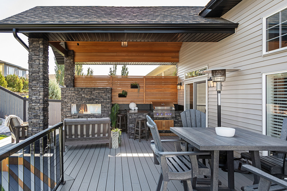 Mid-sized country backyard and ground level deck in Edmonton with with fireplace, a roof extension and glass railing.