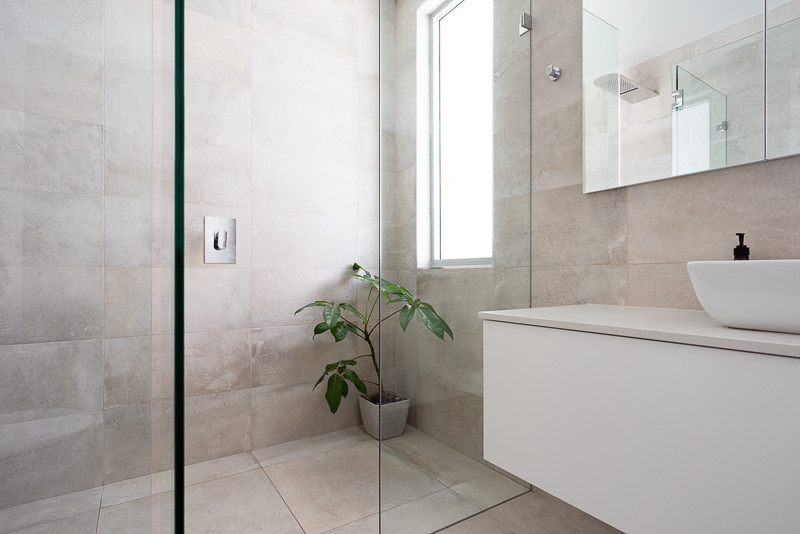 Inspiration for a mid-sized modern master bathroom in Sydney with raised-panel cabinets, white cabinets, a freestanding tub, an open shower, a one-piece toilet, gray tile, stone tile, grey walls, limestone floors, a drop-in sink, engineered quartz benchtops, grey floor, a hinged shower door and white benchtops.