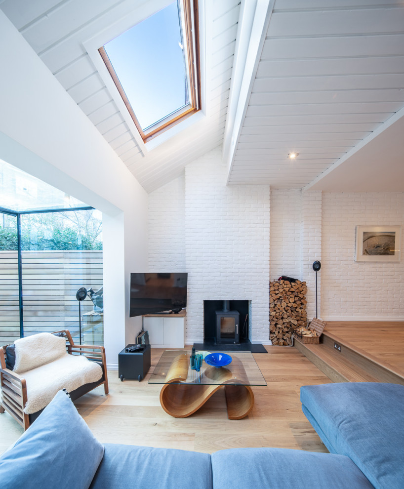 Idées déco pour un salon scandinave ouvert avec un mur blanc, un sol en bois brun, un poêle à bois, un plafond en lambris de bois et un mur en parement de brique.