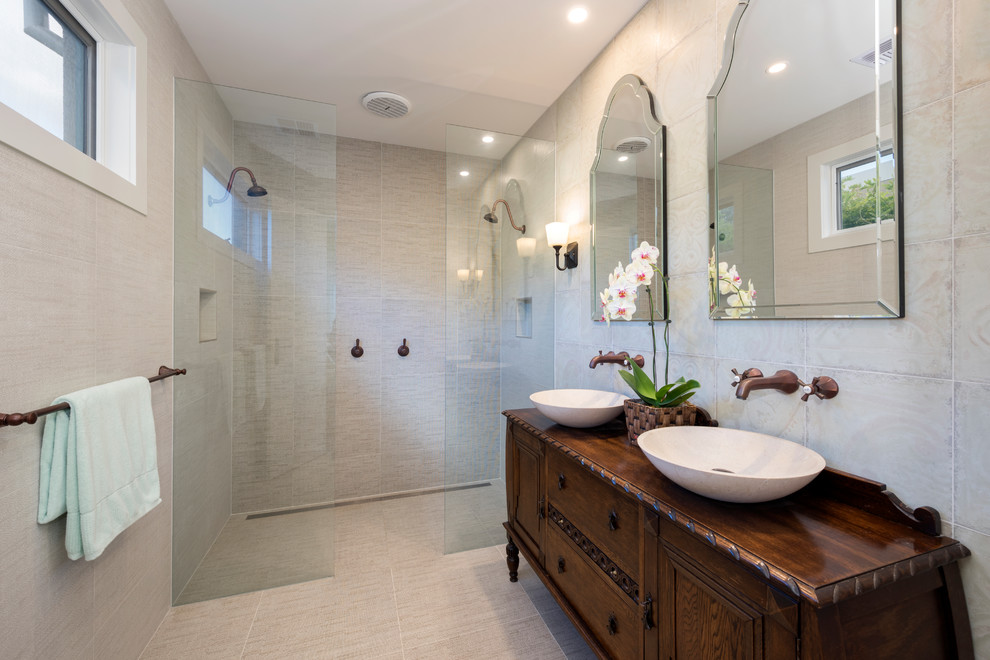 Photo of a mid-sized mediterranean 3/4 bathroom in Melbourne with furniture-like cabinets, medium wood cabinets, a double shower, beige tile, a vessel sink, wood benchtops, porcelain tile, porcelain floors and beige walls.