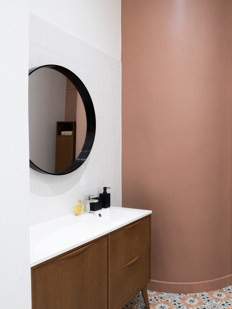 Источник вдохновения для домашнего уюта: туалет среднего размера с коричневыми фасадами, белой плиткой, керамогранитной плиткой, розовыми стенами, полом из цементной плитки, монолитной раковиной, разноцветным полом, белой столешницей и напольной тумбой