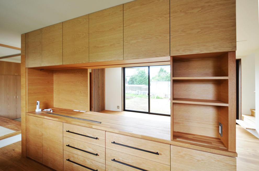 Bild på ett avskilt, mellanstort minimalistiskt brun linjärt brunt kök, med en integrerad diskho, skåp i shakerstil, träbänkskiva, brunt stänkskydd, stänkskydd i trä, integrerade vitvaror, mellanmörkt trägolv, en köksö och brunt golv