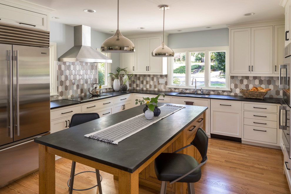 Example of a mid-sized transitional u-shaped medium tone wood floor and brown floor kitchen design in Minneapolis with an undermount sink, recessed-panel cabinets, white cabinets, granite countertops, multicolored backsplash, ceramic backsplash, stainless steel appliances and an island