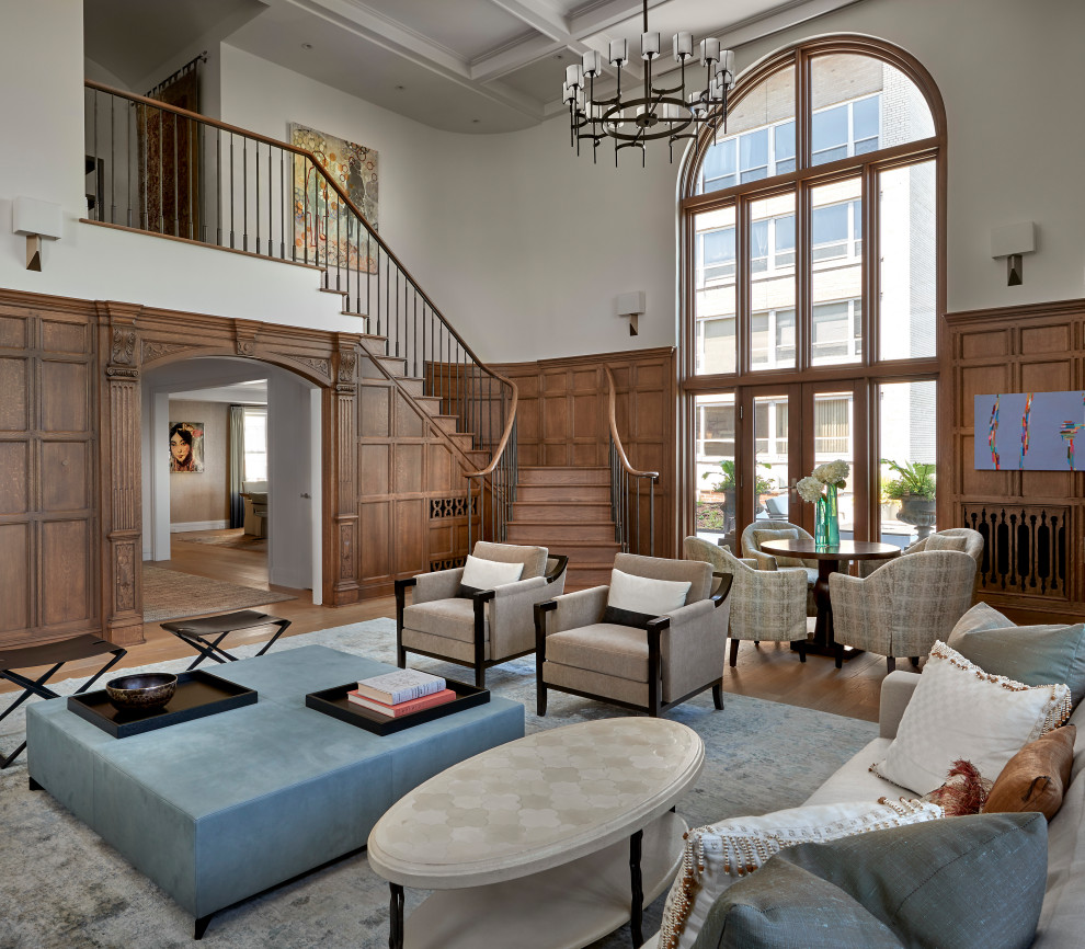 This is an example of an expansive transitional living room in Chicago with white walls, light hardwood floors, brown floor, coffered and panelled walls.