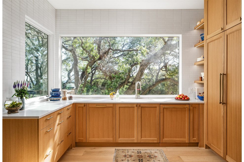 Inspiration for a transitional u-shaped light wood floor and beige floor open concept kitchen remodel in Austin with medium tone wood cabinets, white backsplash, ceramic backsplash, an island, white countertops and stainless steel appliances