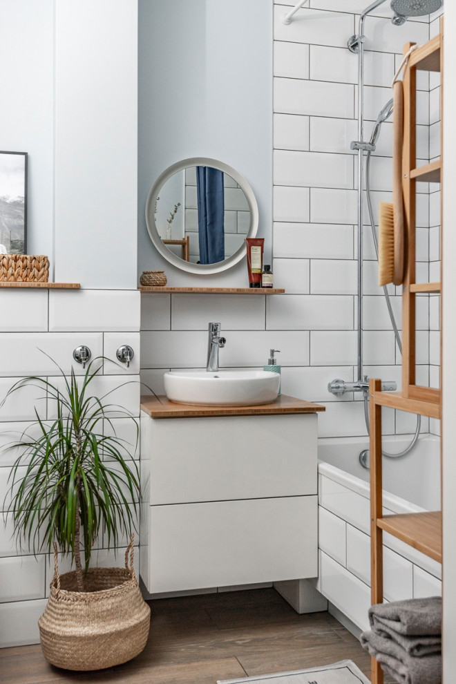 This is an example of a scandinavian master bathroom in Other with flat-panel cabinets, white cabinets, an alcove tub, a shower/bathtub combo, white tile, subway tile, grey walls, wood-look tile, a vessel sink, brown floor, a shower curtain, brown benchtops, a single vanity and a floating vanity.