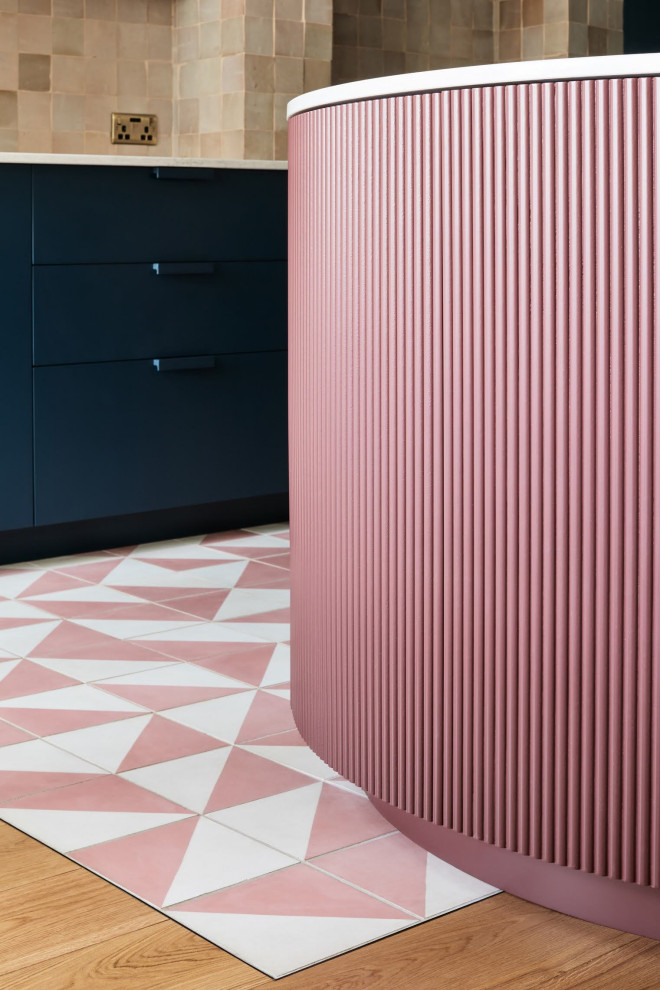 Cette image montre une grande cuisine design en L avec un placard à porte plane, des portes de placard rose, carreaux de ciment au sol, îlot, un sol rose et un plan de travail gris.