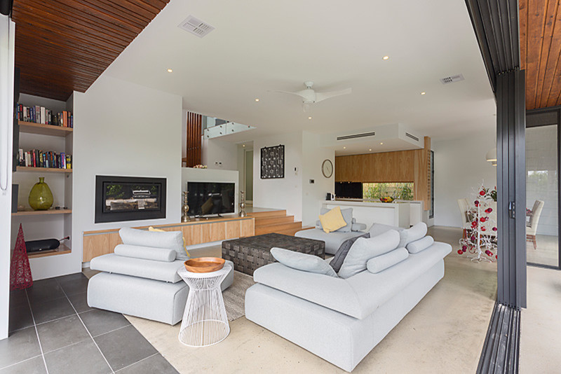 Photo of a large contemporary open concept family room in Other with white walls, concrete floors, a standard fireplace, a plaster fireplace surround and a freestanding tv.