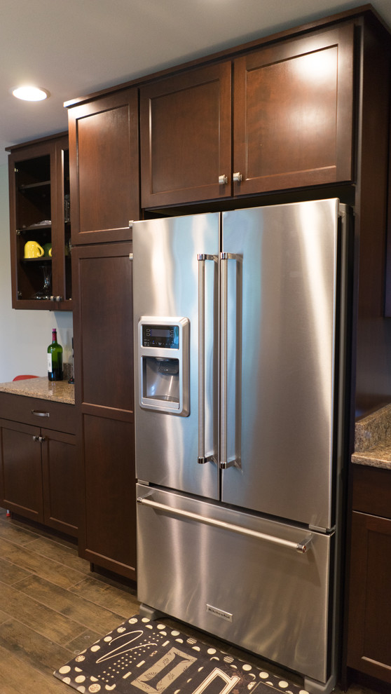 Enclosed kitchen - mid-sized u-shaped ceramic tile enclosed kitchen idea with an undermount sink, shaker cabinets, dark wood cabinets, quartz countertops, brown backsplash, stainless steel appliances and a peninsula