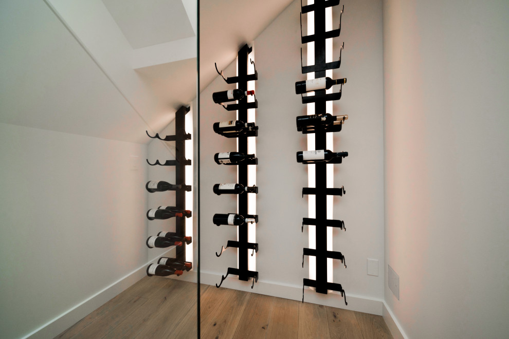 Kleiner Moderner Weinkeller mit hellem Holzboden, Kammern und beigem Boden in Calgary