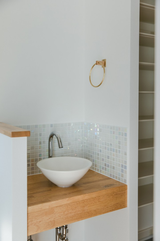 Foto på ett skandinaviskt toalett, med skåp i ljust trä, vita väggar och brunt golv
