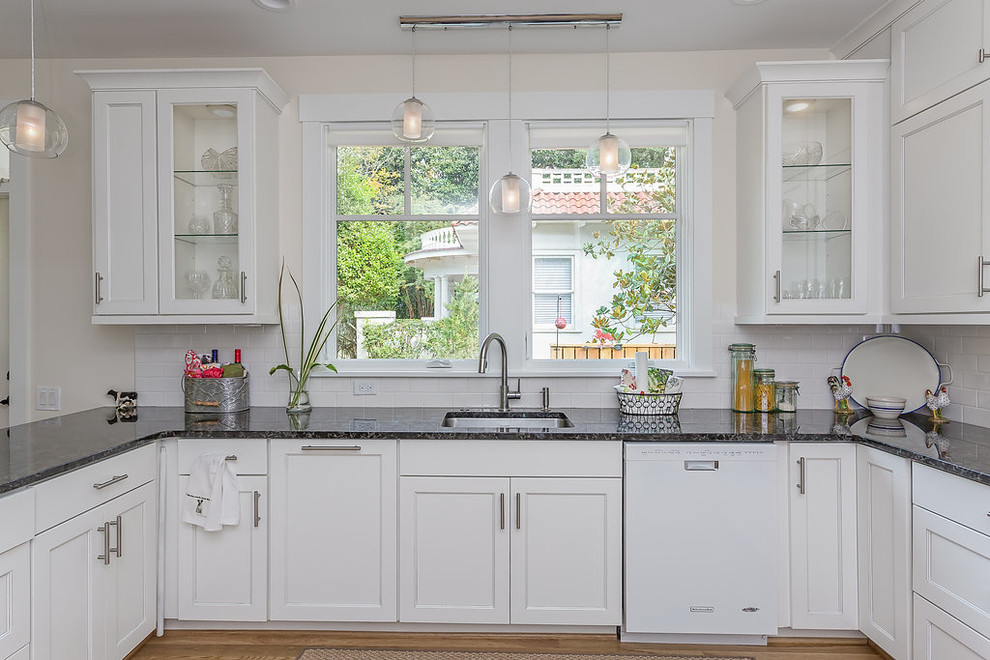 Mid-sized traditional u-shaped eat-in kitchen in Raleigh with a single-bowl sink, flat-panel cabinets, white cabinets, granite benchtops, yellow splashback, ceramic splashback, stainless steel appliances, medium hardwood floors and a peninsula.