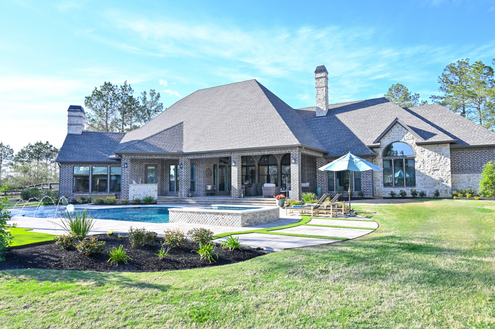 Großes, Zweistöckiges Einfamilienhaus mit Steinfassade, brauner Fassadenfarbe, Schindeldach, schwarzem Dach und Schindeln in Houston