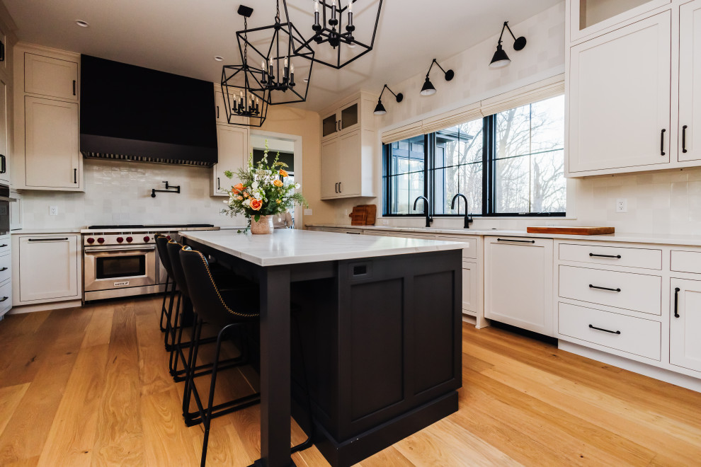 Open concept kitchen - large rustic u-shaped light wood floor open concept kitchen idea with an undermount sink, shaker cabinets, beige cabinets, quartzite countertops, white backsplash, ceramic backsplash, paneled appliances, an island and white countertops