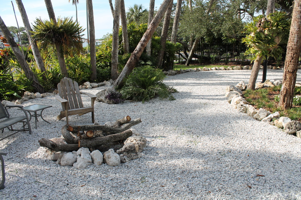 This is an example of a large beach style side yard partial sun xeriscape for summer in Tampa with a fire feature and gravel.