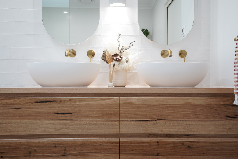キャンベラにある中くらいな北欧スタイルのおしゃれなマスターバスルーム (中間色木目調キャビネット、置き型浴槽、オープン型シャワー、白いタイル、セラミックタイルの床、洗面台1つ、フローティング洗面台) の写真