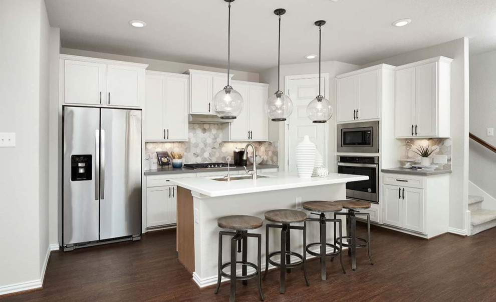 Idéer för ett modernt grå kök, med en undermonterad diskho, luckor med infälld panel, vita skåp, grått stänkskydd, stänkskydd i keramik, rostfria vitvaror, laminatgolv, en köksö och brunt golv