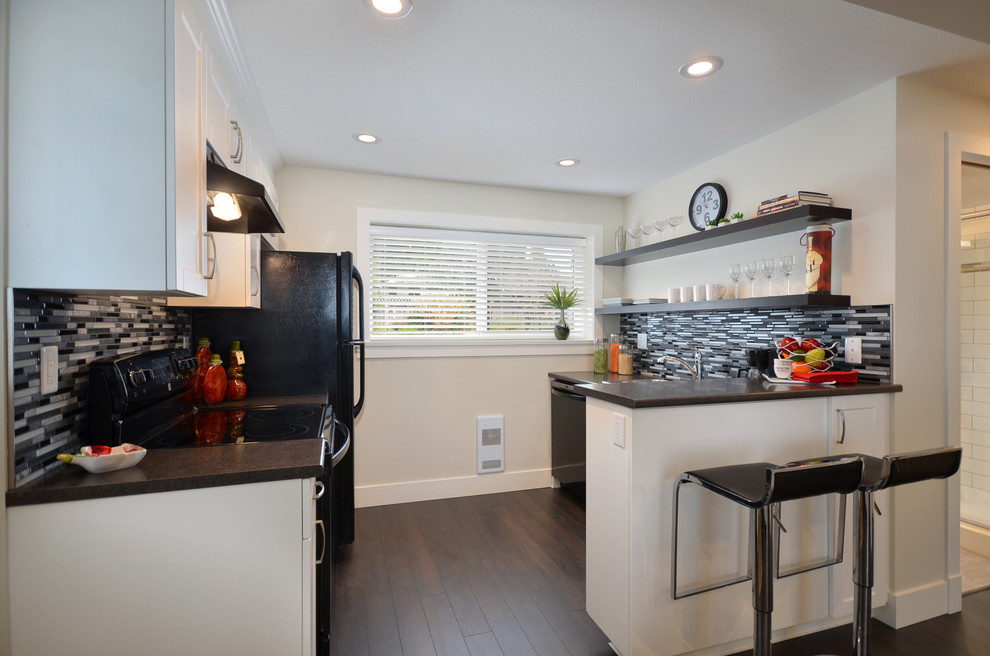 Photo of a contemporary kitchen in Vancouver with matchstick tile splashback, grey splashback and black appliances.