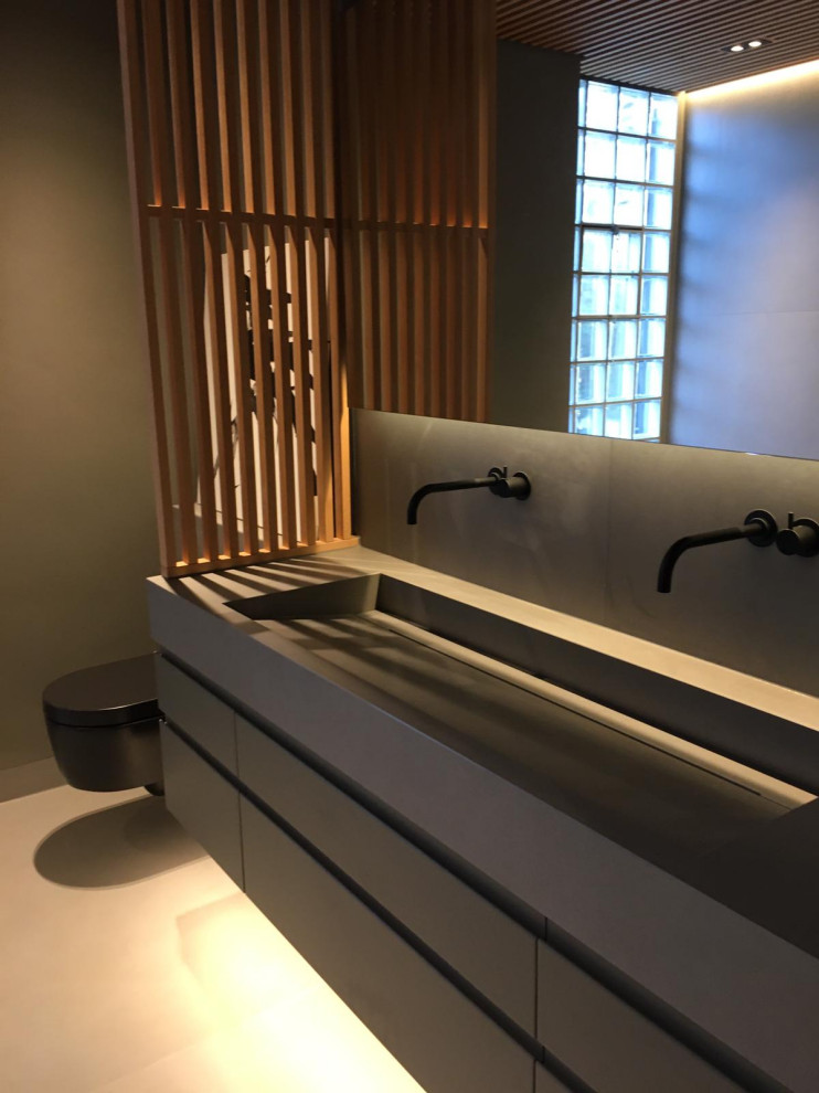 Duschbad With flächenbündigen Schrankfronten, hellen Holzschränken, bodengleicher Dusche, Wandtoilette, grauen Fliesen, Keramikfliesen, grauer Wandfarbe, Keramikboden, Trogwaschbecken, gefliestem Waschtisch, grauem Boden, offener Dusche and grauer Waschtischplatte in Hamburg
