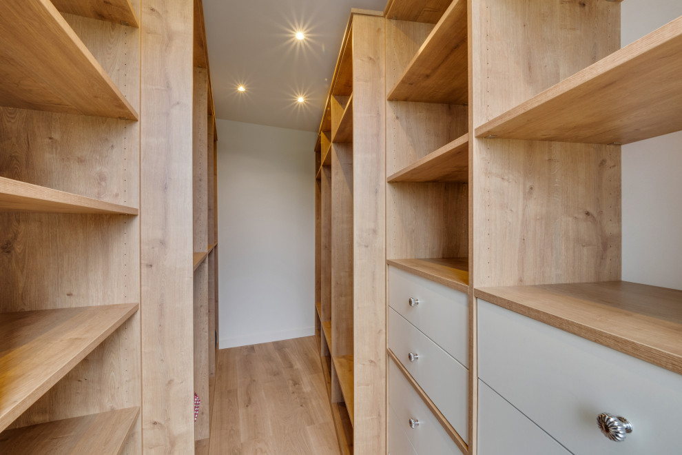 Diseño de vestidor unisex clásico grande con armarios abiertos, puertas de armario de madera clara, suelo de madera clara y suelo beige