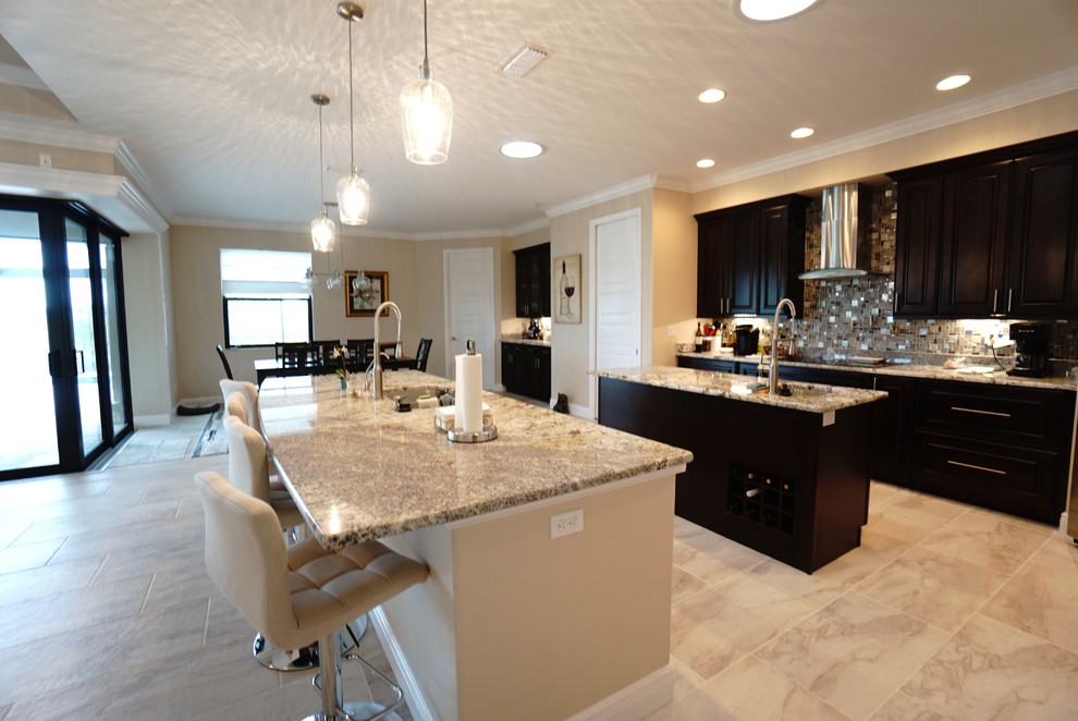 Kitchen - large contemporary ceramic tile kitchen idea in Miami with a drop-in sink, flat-panel cabinets, dark wood cabinets, granite countertops, beige backsplash, ceramic backsplash, stainless steel appliances and two islands