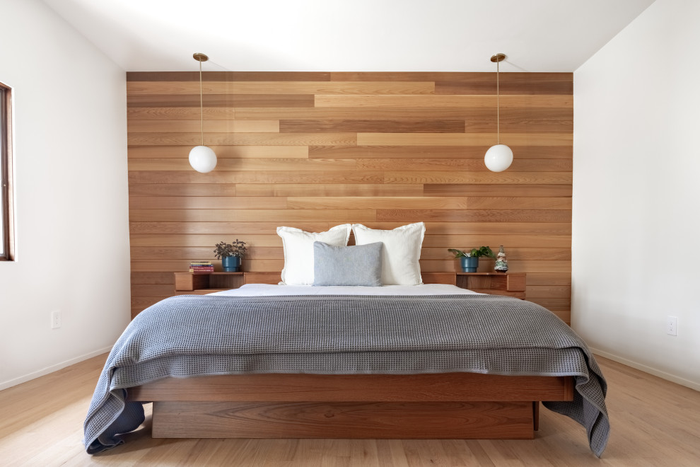 Immagine di una camera matrimoniale minimalista con pareti bianche, parquet chiaro e pareti in legno
