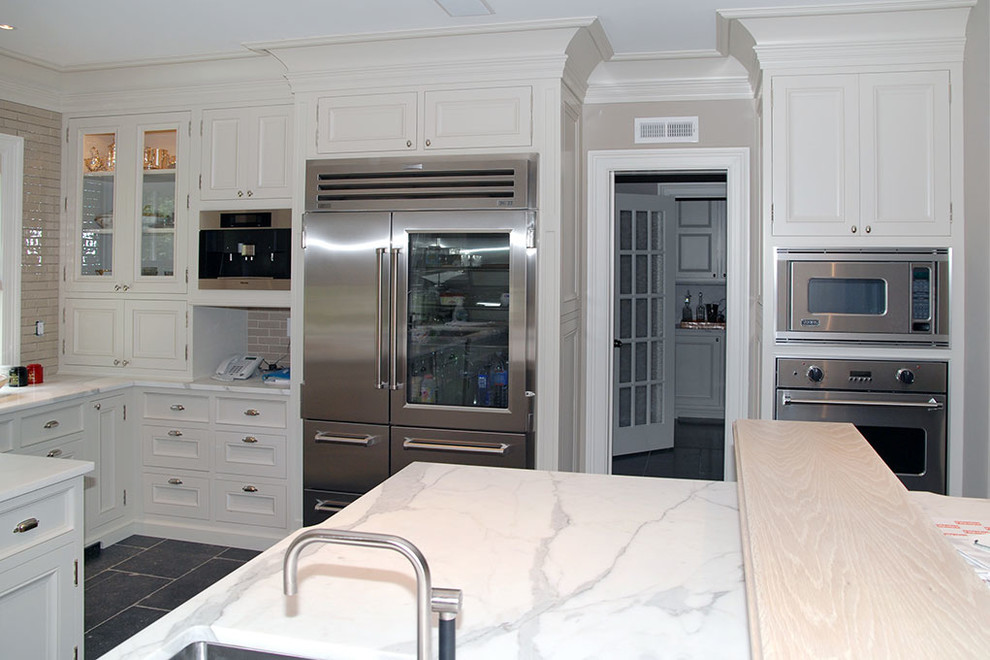 Inspiration for a large transitional u-shaped black floor eat-in kitchen remodel with an undermount sink, recessed-panel cabinets, white cabinets, stainless steel appliances and an island