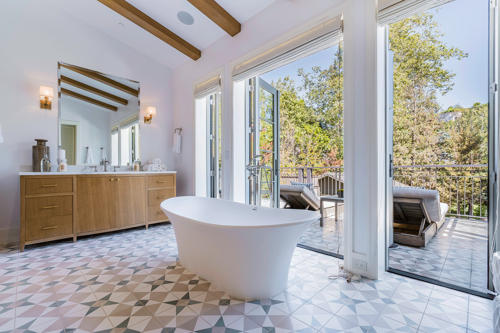 Inspiration for an expansive contemporary master bathroom in Los Angeles with medium wood cabinets, a freestanding tub, white walls, cement tiles, an undermount sink, marble benchtops, multi-coloured floor and flat-panel cabinets.