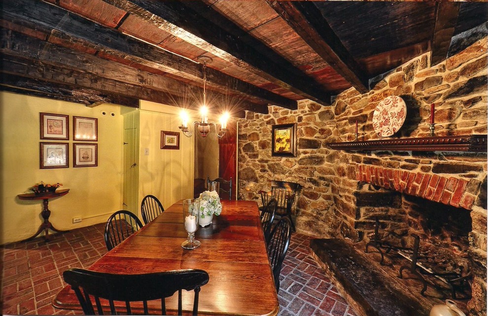 Inspiration for a mid-sized country separate dining room in Philadelphia with brick floors, yellow walls, a standard fireplace and a stone fireplace surround.