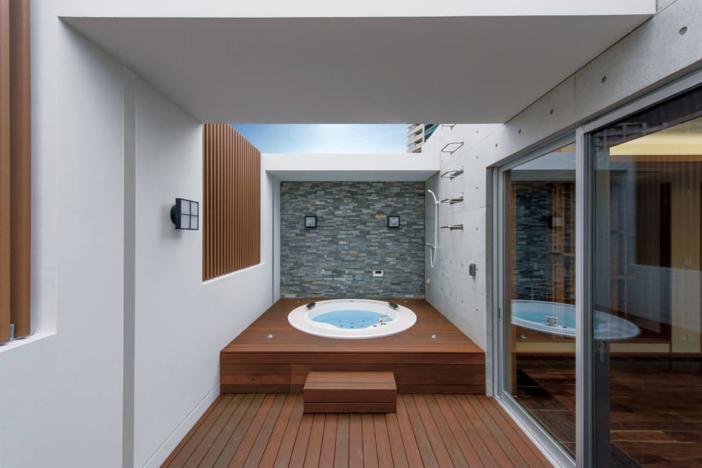 This is an example of a large modern bathroom with a hot tub and gray tile.