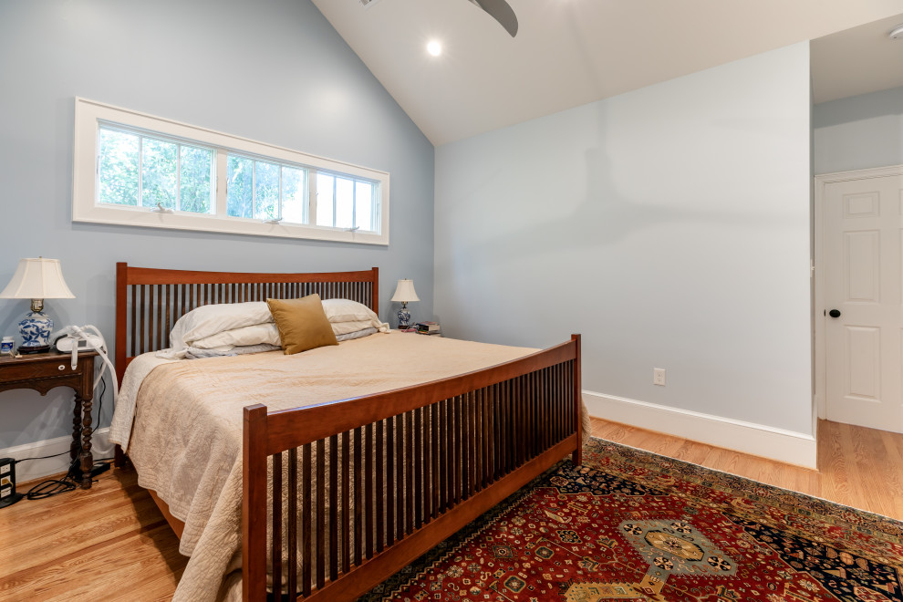 Cette image montre une grande chambre parentale design avec un mur bleu, un sol en bois brun et un sol marron.