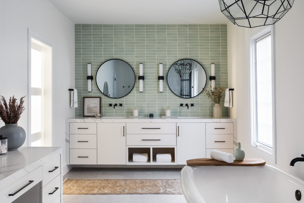 Cette photo montre une salle de bain chic avec un placard à porte plane, des portes de placard blanches, une baignoire indépendante, un carrelage vert, un mur blanc, un lavabo encastré, un sol gris, un plan de toilette blanc, meuble double vasque et meuble-lavabo suspendu.