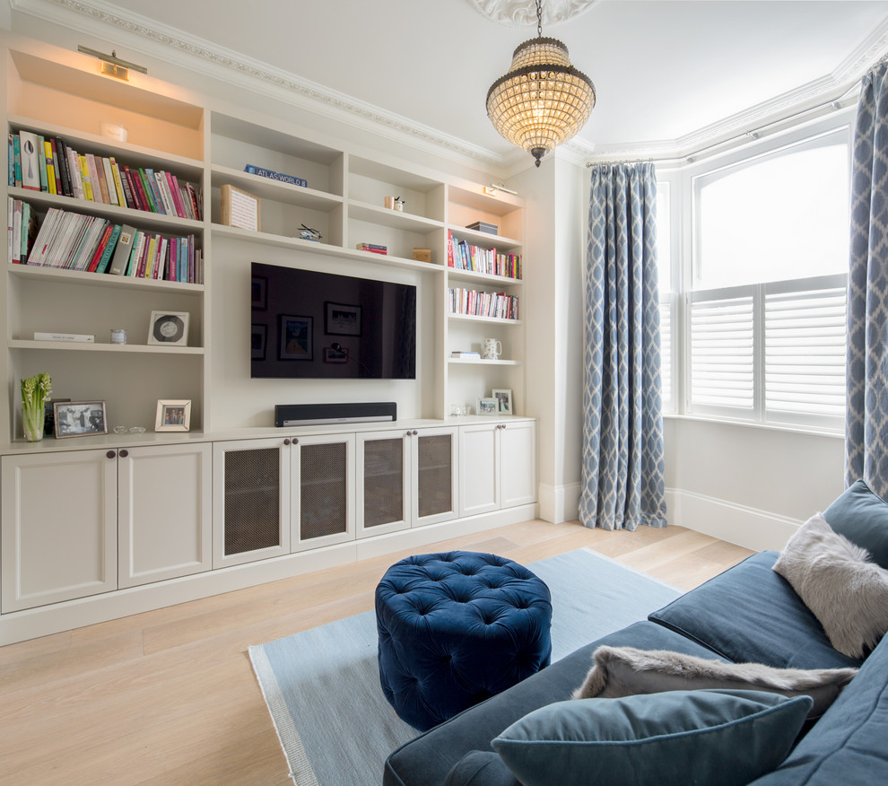 Design ideas for a mid-sized transitional family room in London with a wall-mounted tv, a library, grey walls, light hardwood floors, no fireplace and beige floor.
