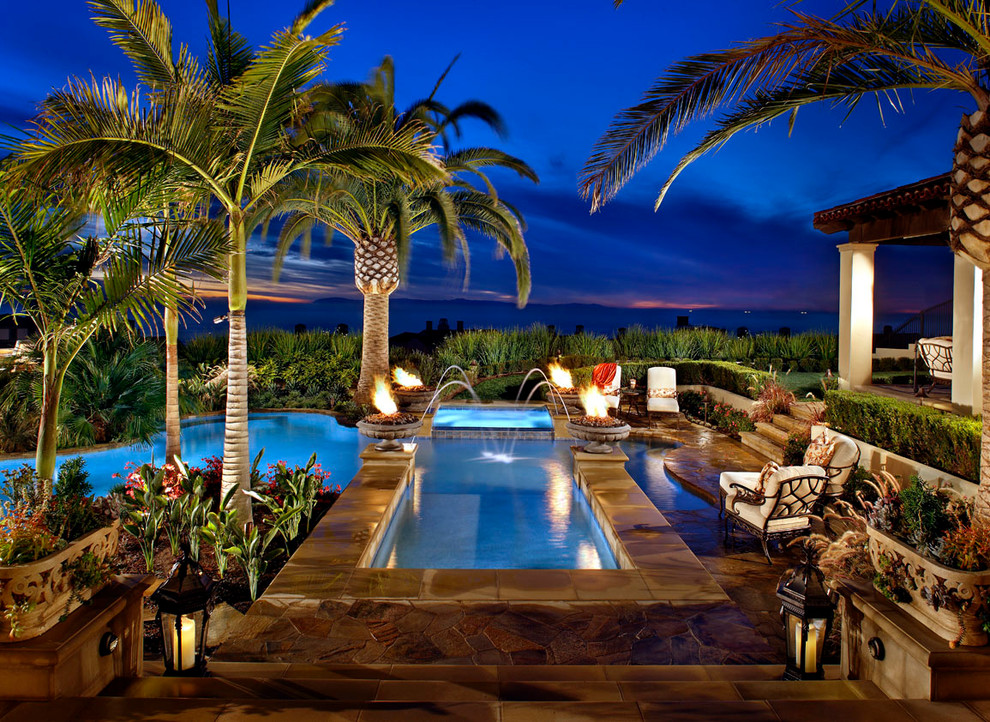 This is an example of a large tropical backyard custom-shaped pool in Orange County with a hot tub and tile.