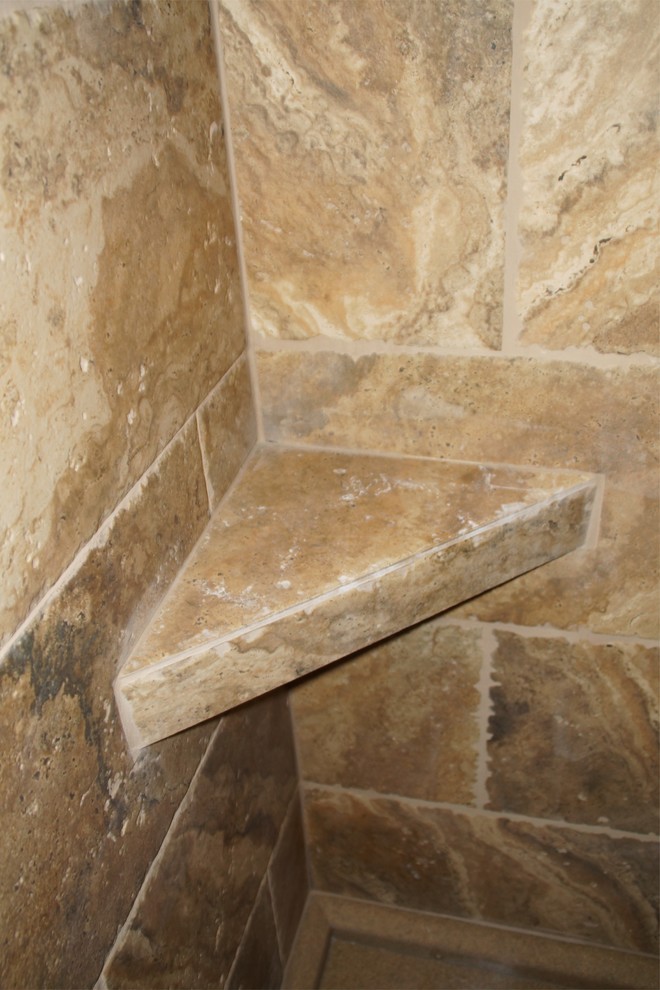 Alcove shower - mid-sized rustic master multicolored tile and stone tile travertine floor alcove shower idea with raised-panel cabinets, medium tone wood cabinets, a one-piece toilet, beige walls, an undermount sink and granite countertops